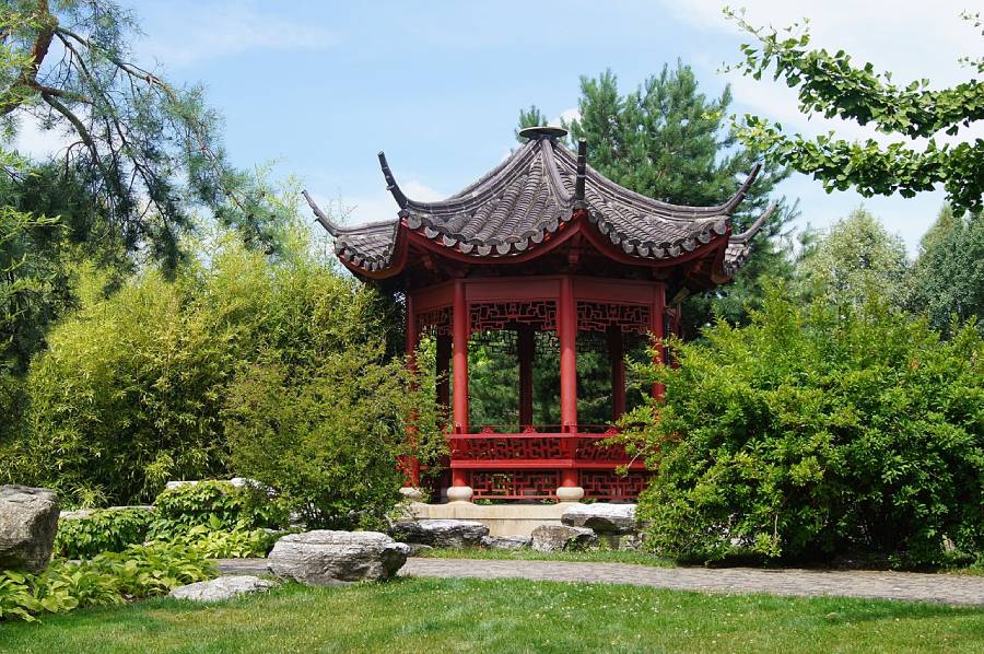 Pavillon chinois rouge au milieu d’un jardin verdoyant, évocation du printemps